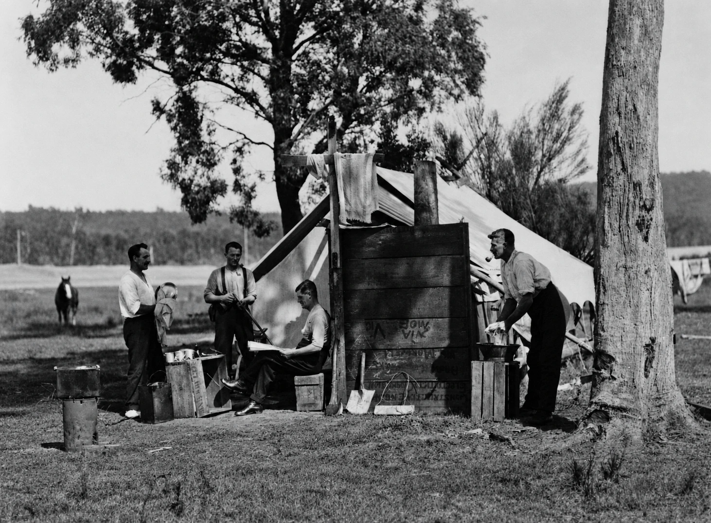 Four men stand beside a canvas tent and a rough timber screen at Yallourn in the 1920s; the man on the right is identified as J. Meddlemess.