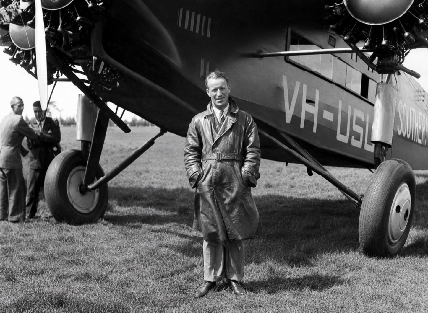 Restored black-and-white photograph of Sir Charles Kingsford Smith standing beside the Southern Cross aircraft at Morwell in 1932.