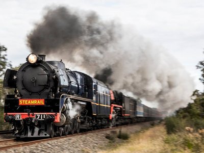 A heritage R Class locomotive departing Moe railway station on a winter's day, with passengers visible through the windows of polished wooden carriages.
