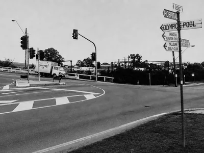 Historic black-and-white streetscape in Moe with road signs pointing to local destinations