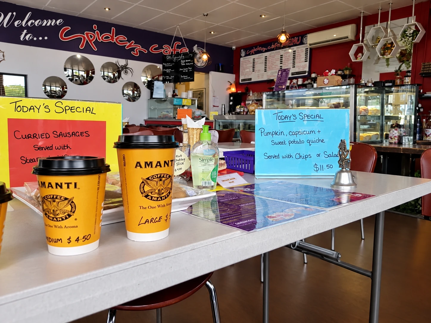 Takeaway coffee cups and handwritten specials inside Spiders Cafe