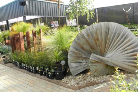 Grasses and garden materials arranged beside a large circular metal garden feature.