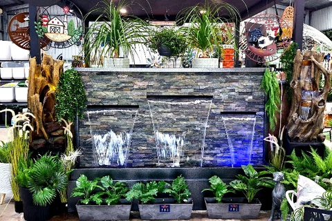 A stone water feature surrounded by lush plants and garden pieces inside Traralgon West Nursery.