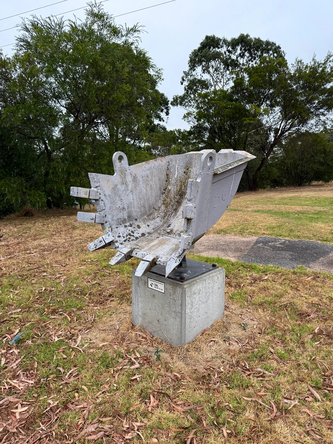 Dredger bucket with its complete row of teeth mounted on a concrete block at PowerWorks.