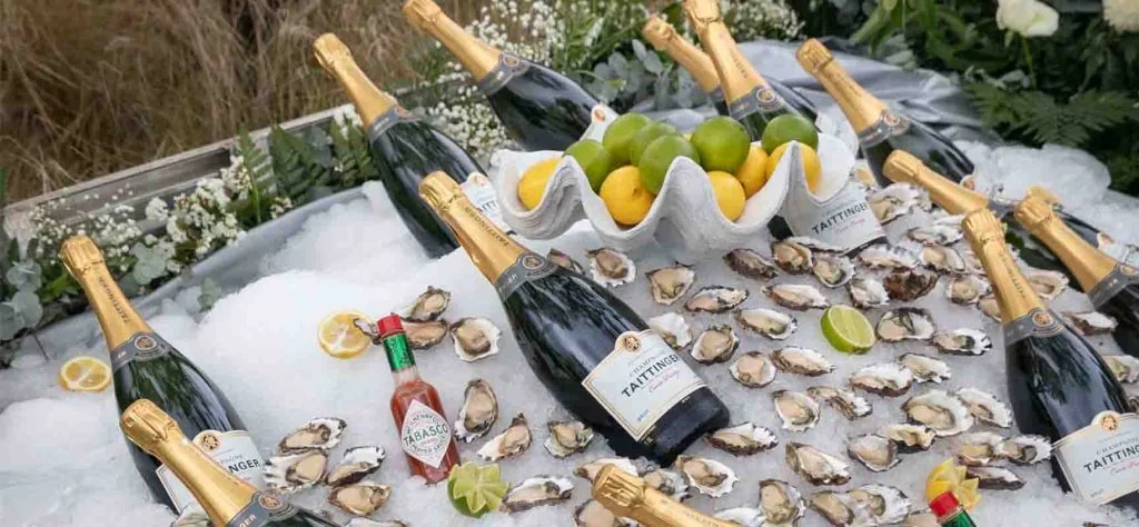 Oysters, citrus and bottles of sparkling wine arranged on ice.