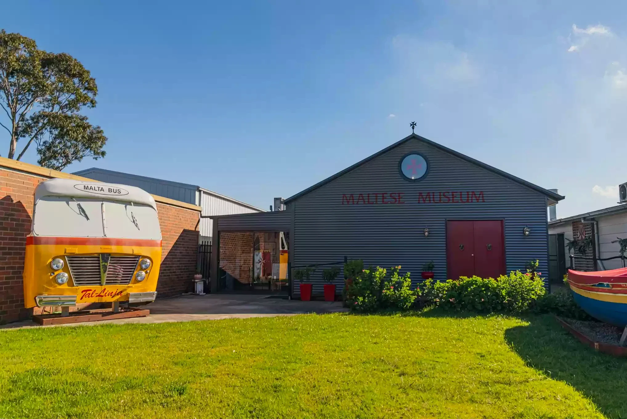 The Maltese Museum exterior with a colourful Malta bus display and boat.