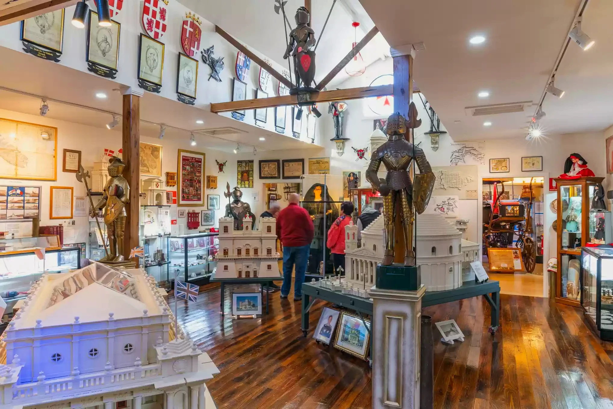Visitors stand among architectural models and armoured figures inside the Maltese Museum.