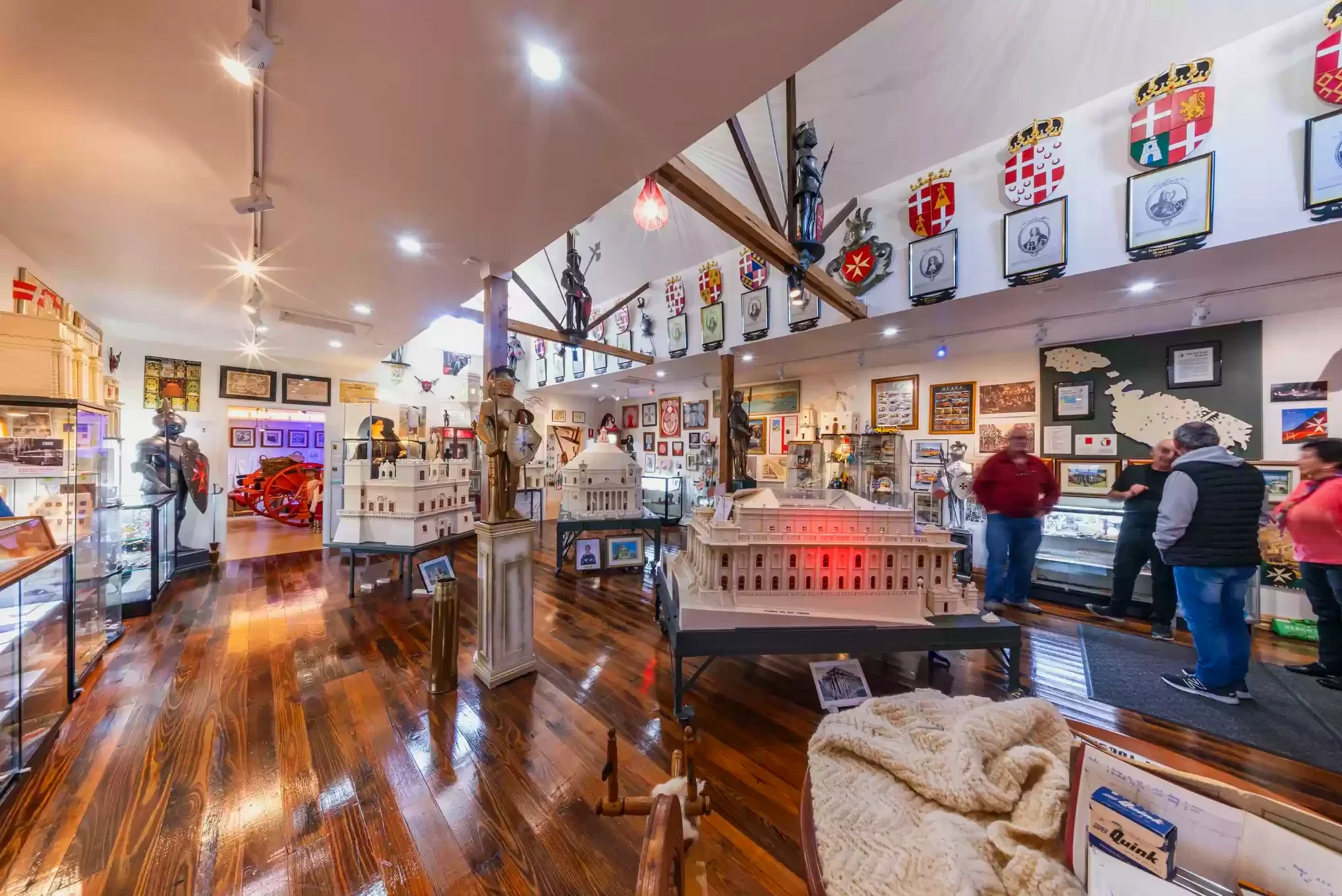 Visitors gather beside miniature buildings and collection displays in the Maltese Museum.