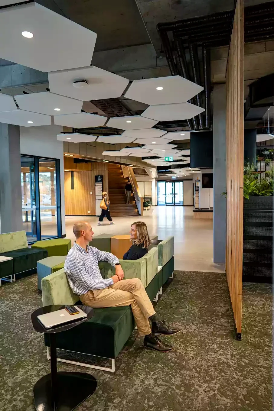 Two people talk in a shared lobby beneath geometric acoustic panels at Morwell Innovation Centre.
