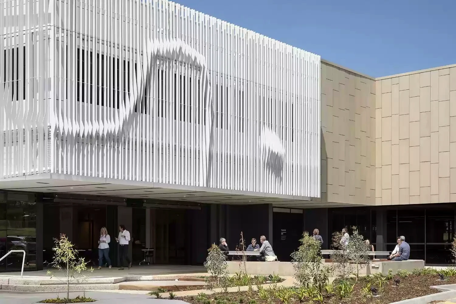 Small groups meet outside beneath the screened façade of Morwell Innovation Centre.