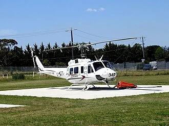 A white emergency-service helicopter standing on a concrete helipad.